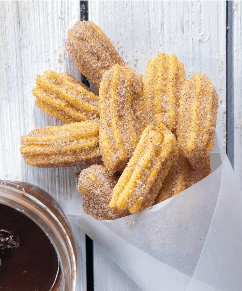 An easy BAKED homemade Mexican churros bites recipe with a chocolate dipping sauce! A deliciously ‘healthy’ way to get an authentic churro! Vegan? Make them eggless! You can easily prepare these tasty mini churros WITHOUT a piping bag too!