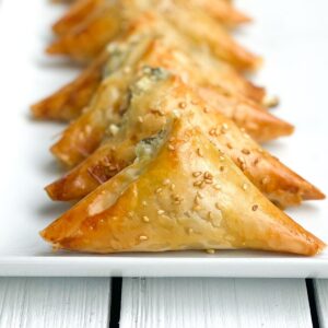 mini spinach pies on a white plate lined up