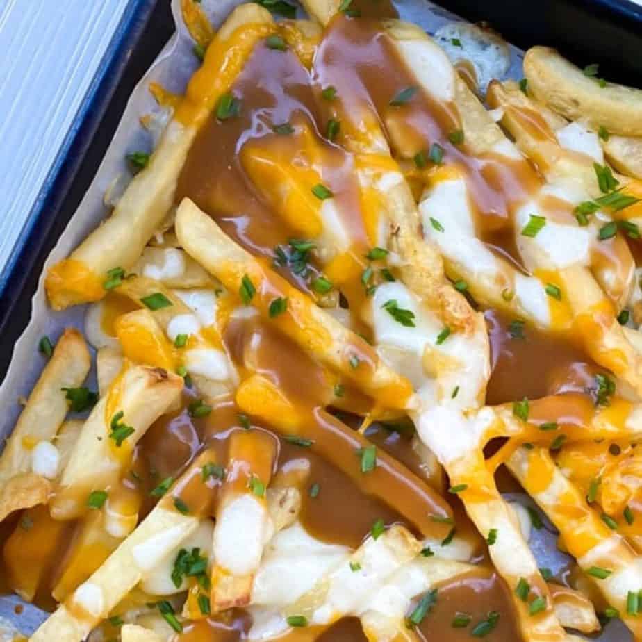 steak cut french fries with melted mozzarella cheese and gravy on a baking sheet
