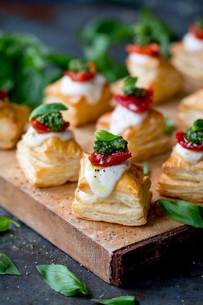 squares of puff pastry topped with cheese, tomato slice and pesto