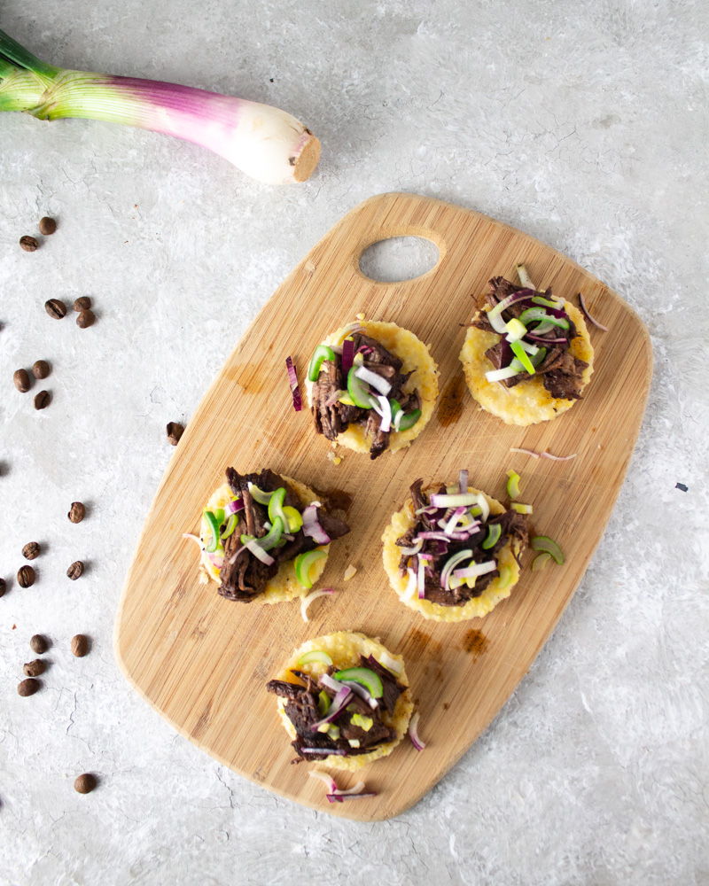 round polenta bites topped with lamb on a cutting board