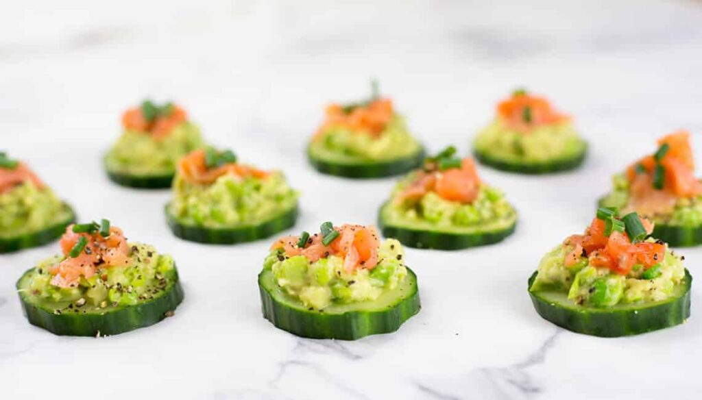 smoked salmon on top of slices of cucumber on a table