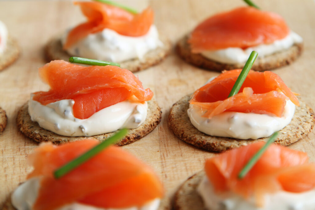salmon and cheese on a cracker with a chive garnish
