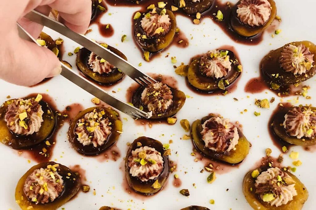 apricots stuffed with cheese and topped in a pomegranate glaze on a white plate