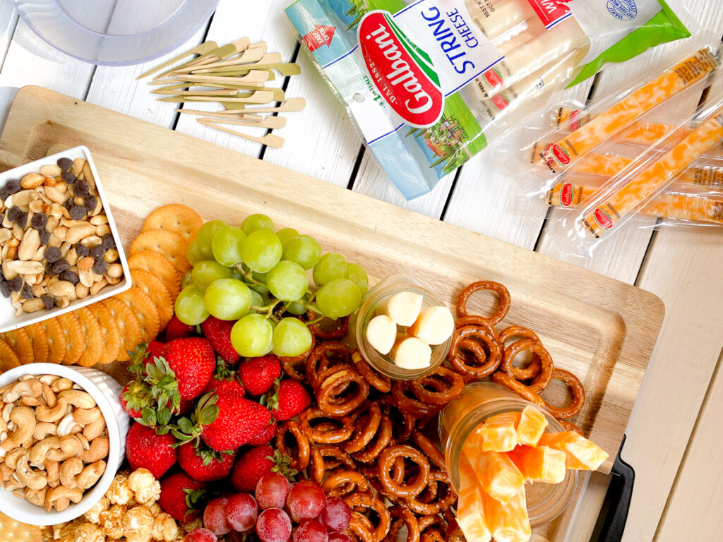 kid friendly charcuterie board with pretzels, nuts, cheeses and fruit