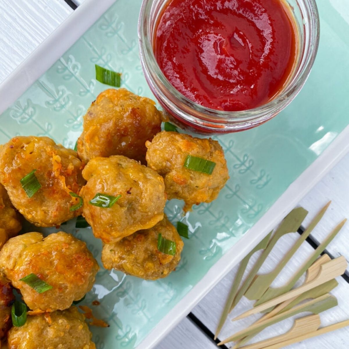 Sausage balls without pancake mix on a plate with ketchup and skewers.